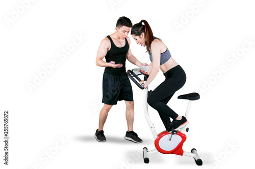 Trainer helps her client to exercise with fitness bicycle