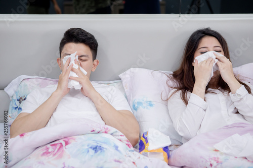 Unhealthy couple wiping their nose on the bed