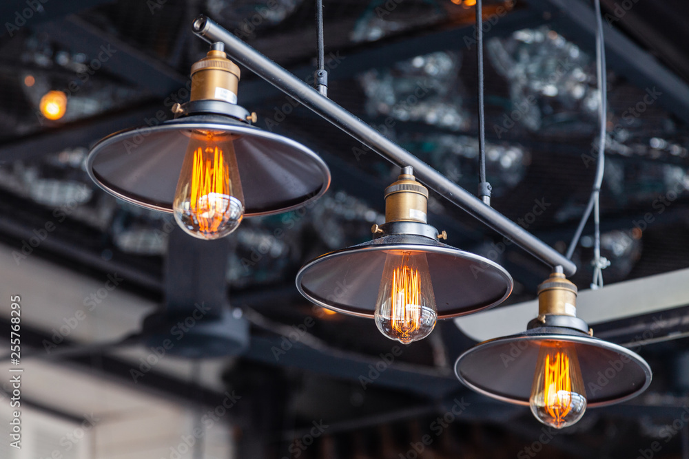Black iron loft chandeliers with edison lamps on a black background, bokeh. Concept of modern interior design of restaurant, cafe, apartment, office, shop, wine bar