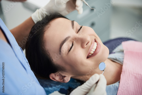 Charming young woman with straight white teeth visiting dentist