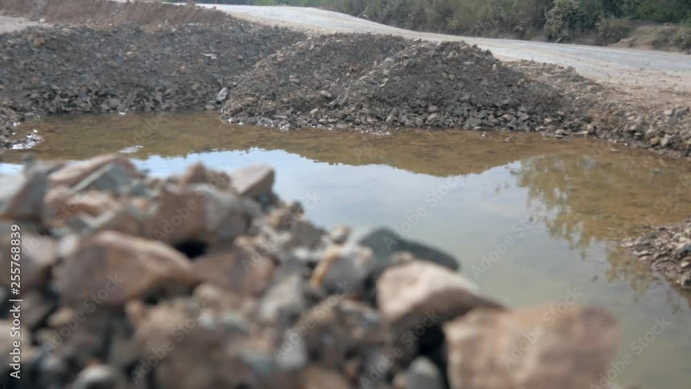 Closeup of rocks on a excavated work site with a small pond & reflections on the water Closeup of rocks on a excavated work site with a small pond & reflections on the water