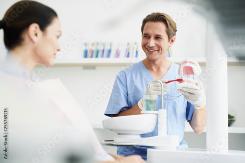Cheerful dentist showing how to clean teeth properly and right