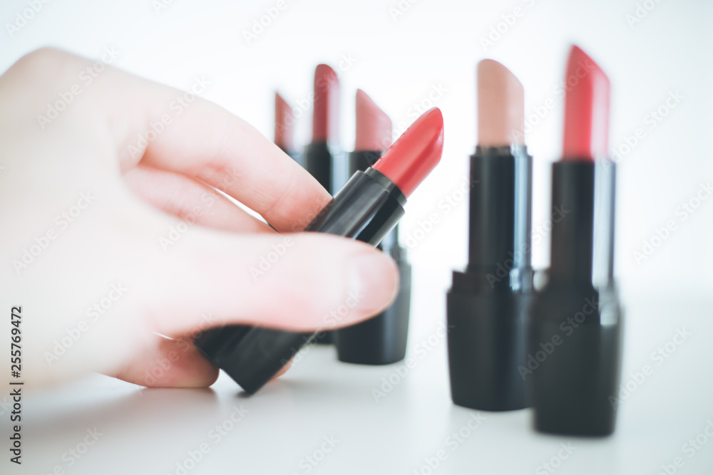 Obraz premium Taking a lipstick: Female hand is taking an elegant, red lipstick