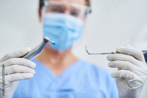 Male dentist in sterile gloves demonstrating dental tools