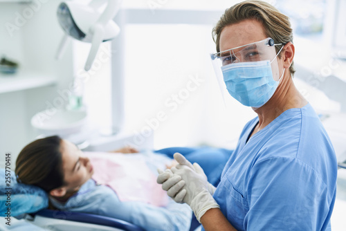 Handsome dentist in protective mask feeling satisfied after dental procedure
