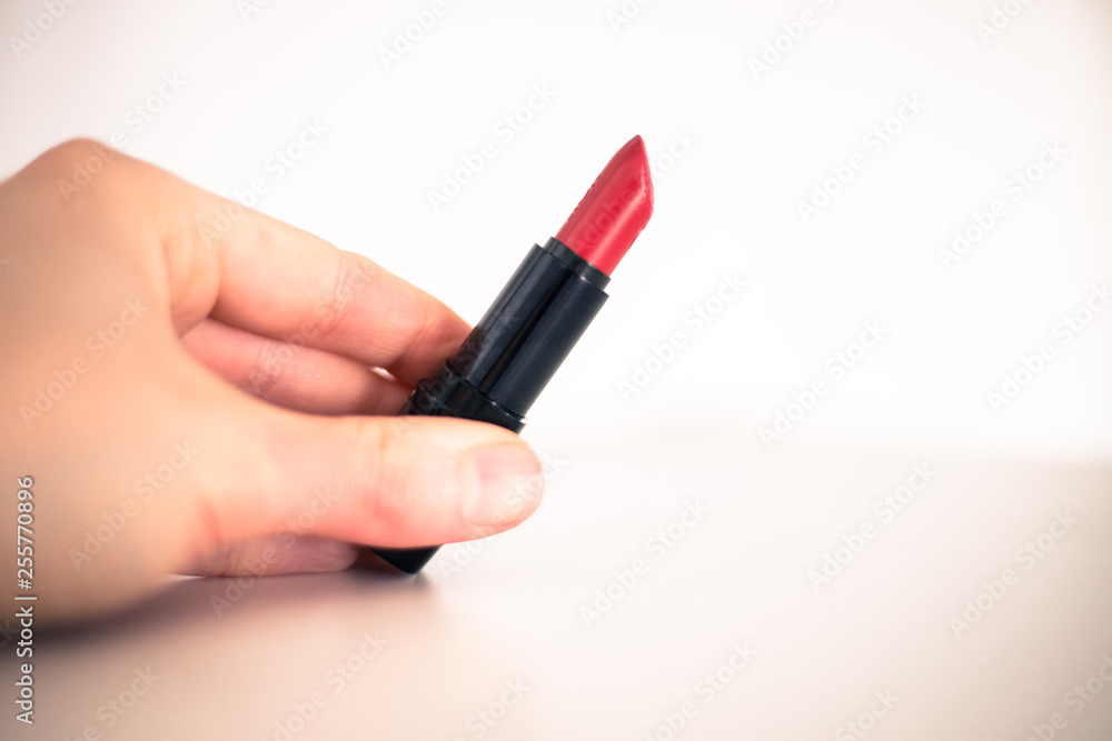 Taking a lipstick: Female hand is taking an elegant, red lipstick Taking a lipstick: Female hand is taking an elegant, red lipstick