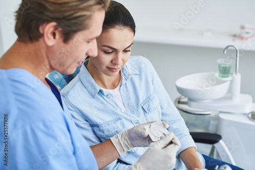 Male dentist and young lady looking at braces