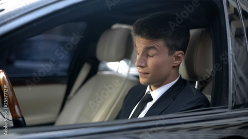 Tired businessman with closed eyes sitting in car, feeling sleepiness, insomnia © motortion