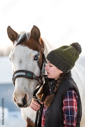 teenag girl holding her handsome horse. Winter scene with snow in background