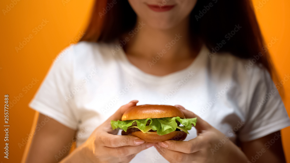 Girl holding home-made burger with lettuce inside, delicious snack, close up Girl holding home-made burger with lettuce inside, delicious snack, close up