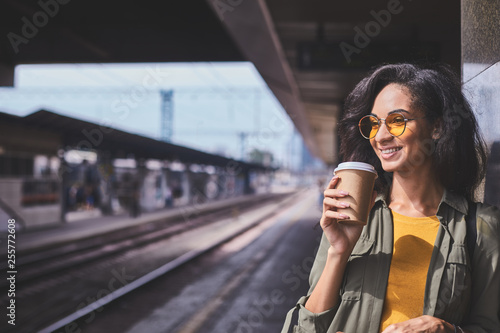 Stylish woman drinking take away coffee at railway station
