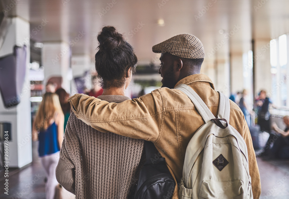 Rear view of a loving couple walking along the railway station