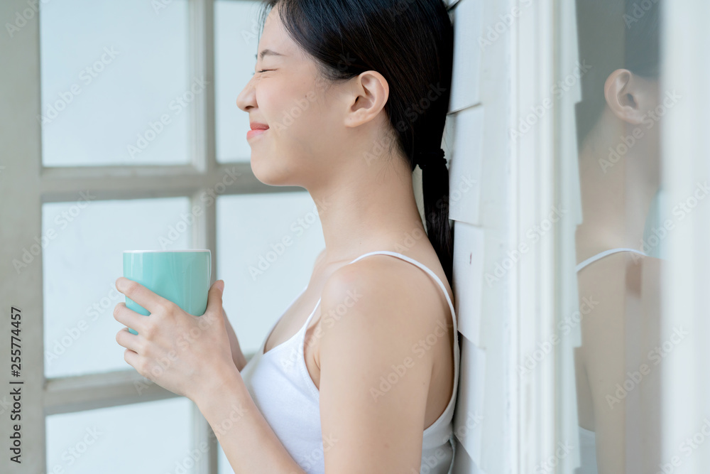 beautiful asian teen white Tank top happiness smile enjoy freshness morning with hot drink near window with sun light beautiful asian teen white Tank top happiness smile enjoy freshness morning with hot drink near window with sun light