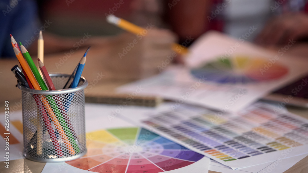 Colored pencils standing in metal holder, designers looking at color spectrum Colored pencils standing in metal holder, designers looking at color spectrum