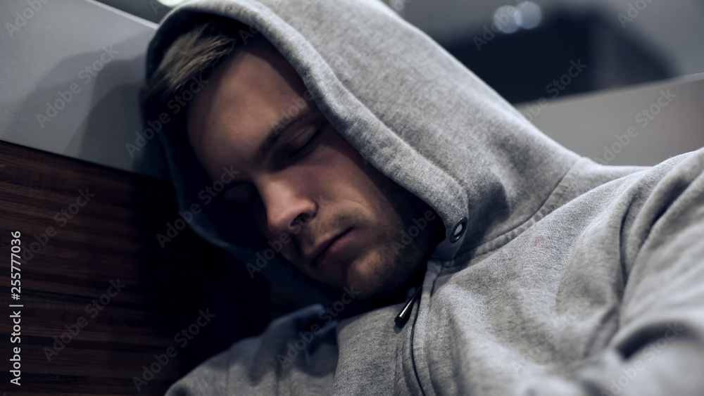 Fototapeta premium Homeless man in hoodie sleeping in public transport, unemployment problems