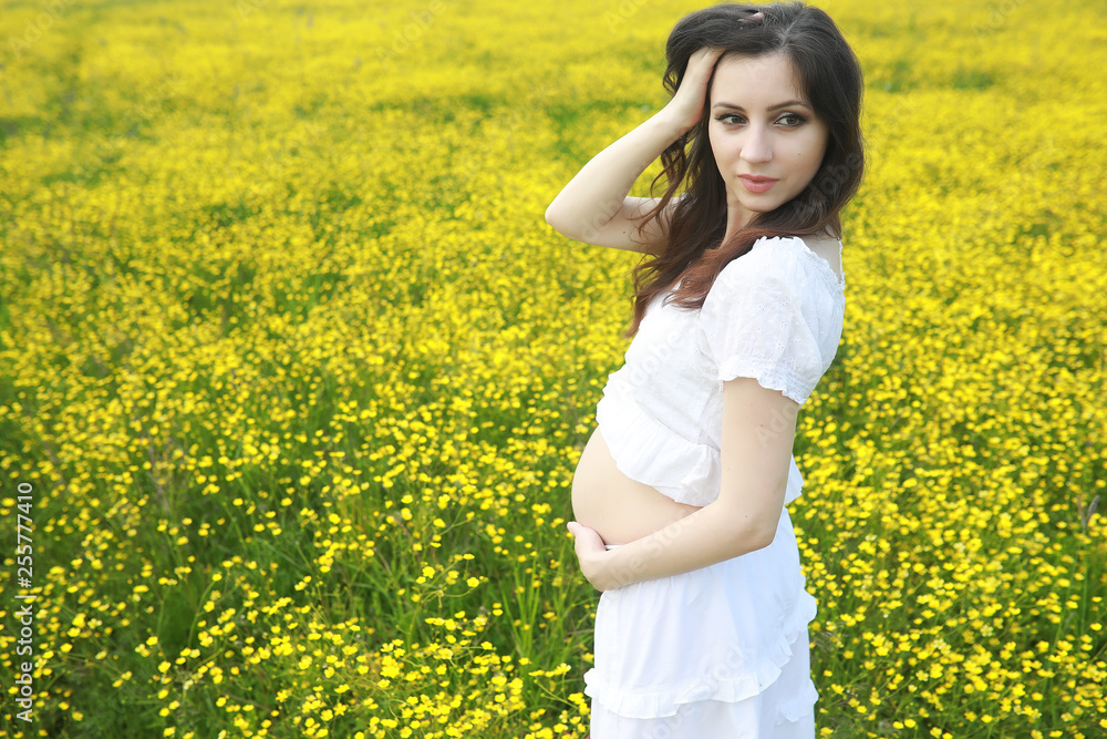 Pregnant woman in a dress in a field of flowers Pregnant woman in a dress in a field of flowers