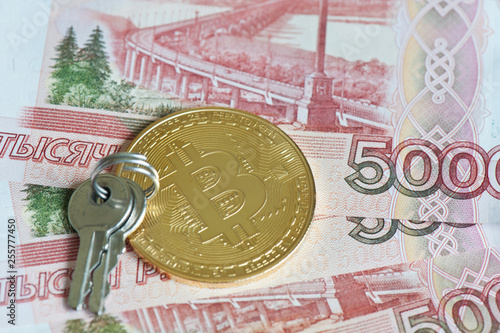 Golden bitcoin and two keys against 5000 rubles banknotes background. Cryptocurrency