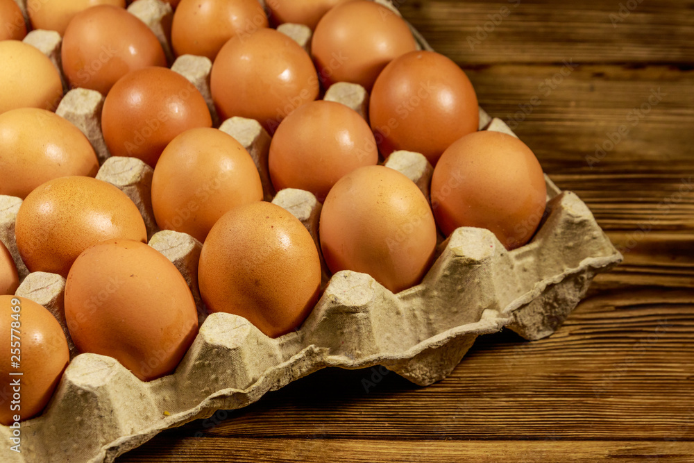 Raw chicken eggs in cardboard pack on wooden table Raw chicken eggs in cardboard pack on wooden table