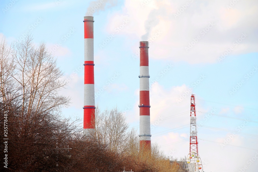 two factory chimneys of them smoke against the blue sky two factory chimneys of them smoke against the blue sky