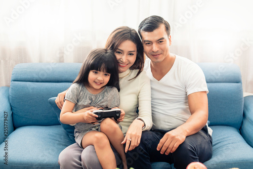 happy family mixed race mom dad and daughter enjoy watching tv show or game play together weekend activity home background