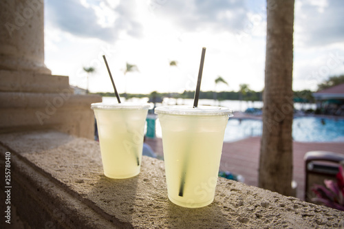 Two delicious glasses of lemonade poolside at a tropical outdoor resort. Selective focus on the two glasses on a hot summer day