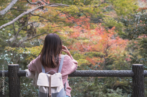 Lonely woman standing absent minded and looking at leaves change color in autumn