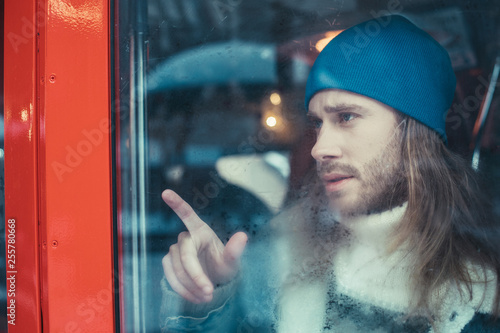 Happy hipster man pointing from bus window