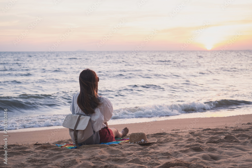 Young traveler woman relaxing on tropical beach at sunset