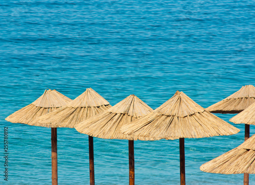 Fototapeta Naklejka Na Ścianę i Meble -  Straw umbrellas on a  beach with turquoise water