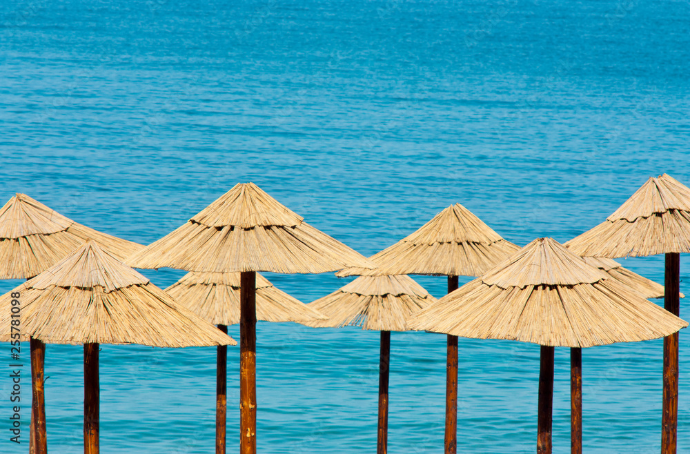 Straw umbrellas on the beach with turquoise water