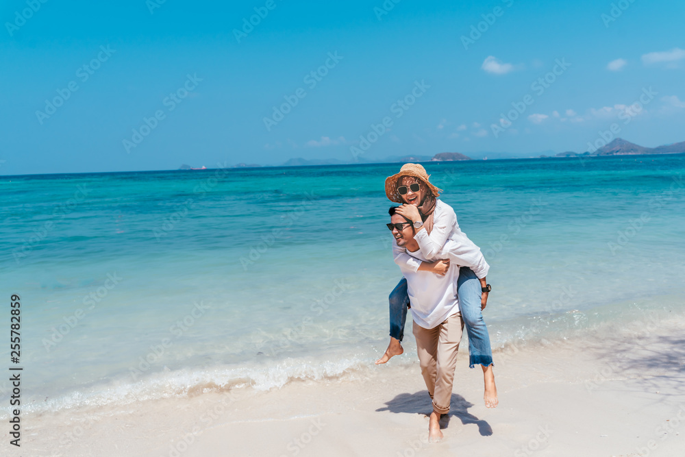 Young happy muslim couple white dress on seashore. Travel Vacation Retirement Lifestyle Concept. Man giving piggyback ride to girlfriend on the beach on the beach in vacation day. summer time.