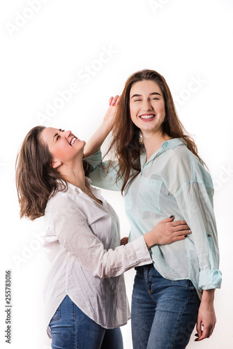 Two young girls hug and laugh indoors