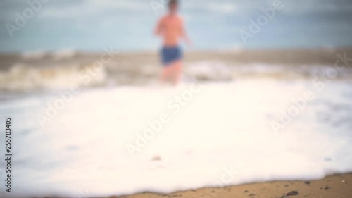 Young male swimmer walking out of the sea slow motion