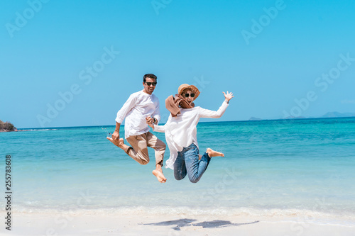 Young happy muslim couple white dress on seashore. Travel Vacation Retirement Lifestyle Concept. young couple jumping on the beach in vacation day. summer time.