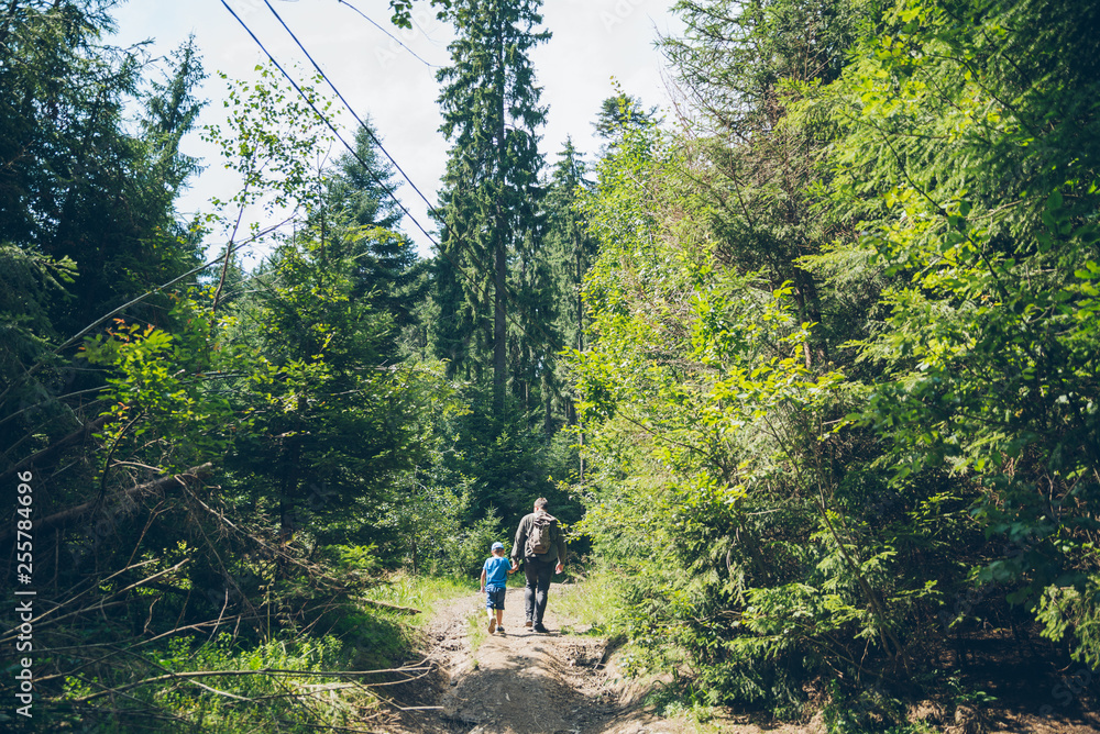 father with little son walking by forest trail father with little son walking by forest trail