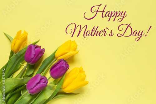 Yellow and purple flowers tulips in a bouquet on a yellow background and the inscription happy mother's day, a festive spring background greeting card