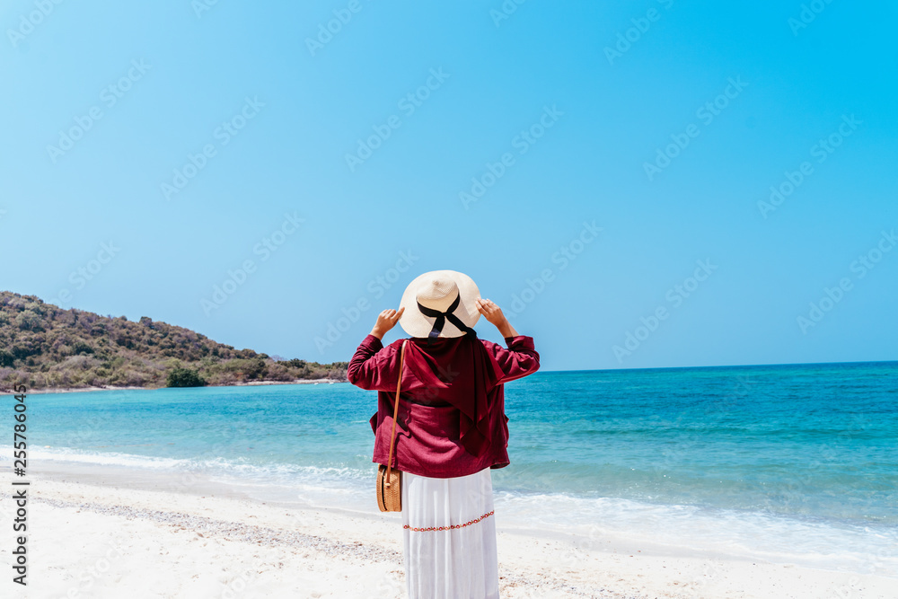Back view of young muslim asian woman looking over the sea. Future and research concept. Happy woman with hands up standing on over sea. Travel concept, Concepts of winner, freedom, 