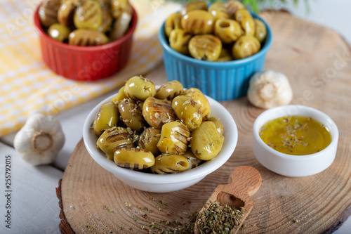 Wooden background with green olives, olive oil, garlic and spices, food background.