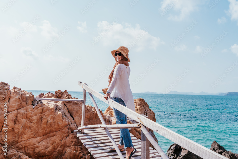 Back view of young asian woman looking from Wood bridge. Woman standing on Wood bridge over sea. Travel mood, Travel concepts.