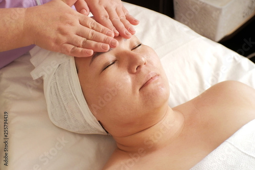 Beautician prepares the woman's face for cosmetic procedures. Close-up. The procedure for applying moisturizer in the beauty salon.