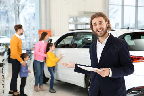 Car salesman with tablet and blurred family near auto on background © New Africa