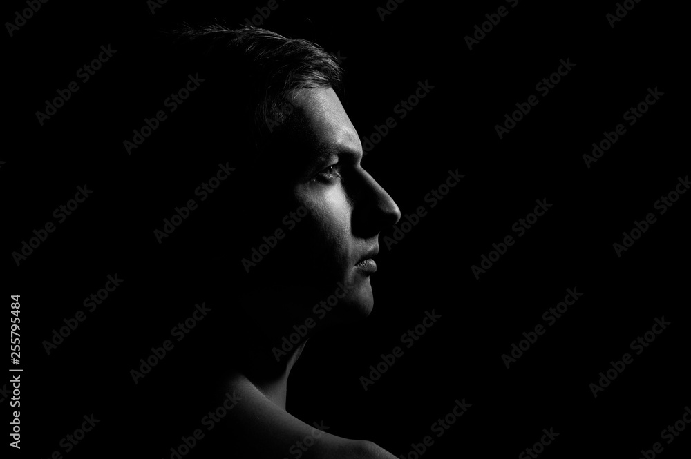 Dramatic portrait of a guy on a black background, black and white