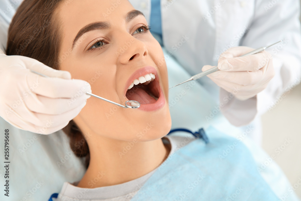 Dentist examining patient's teeth in modern clinic Dentist examining patient's teeth in modern clinic