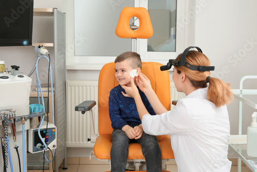 Professional otolaryngologist examining little boy in clinic. Hearing disorder