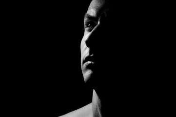 Dramatic portrait of a guy on a black background, black and white photography