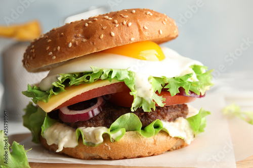 Tasty burger with fried egg on wooden board