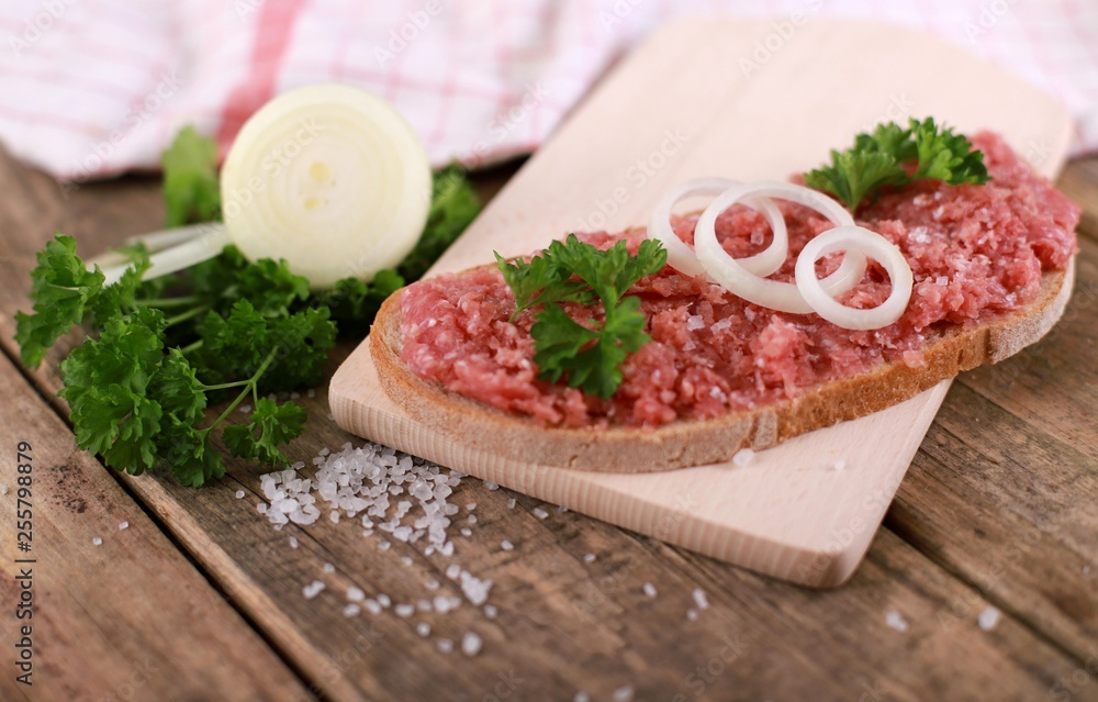 slice of bread with minced meat, parsley and onions - on rustic wooden table - breakfast bread - pork mett slice of bread with minced meat, parsley and onions - on rustic wooden table - breakfast bread - pork mett