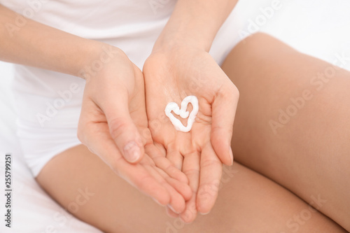 Young woman with heart made of cream on her hand, closeup. Beauty and body care