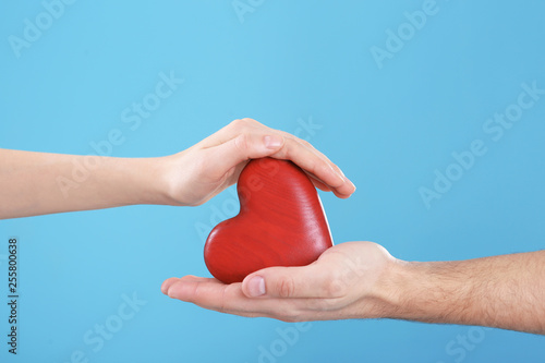 Man and woman holding decorative heart on color background  closeup