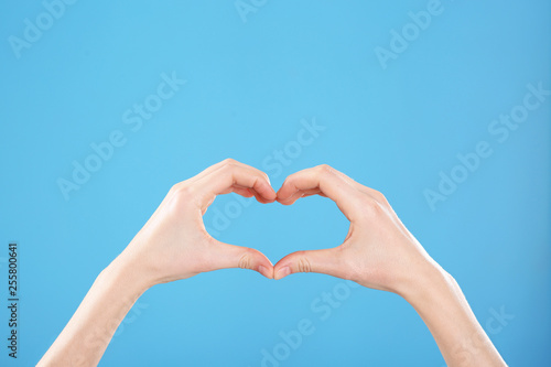 Woman making heart with her hands on color background  closeup